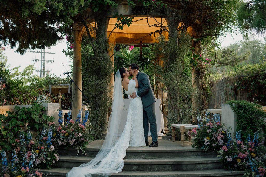 Couple kissing at a floral wedding ceremony.