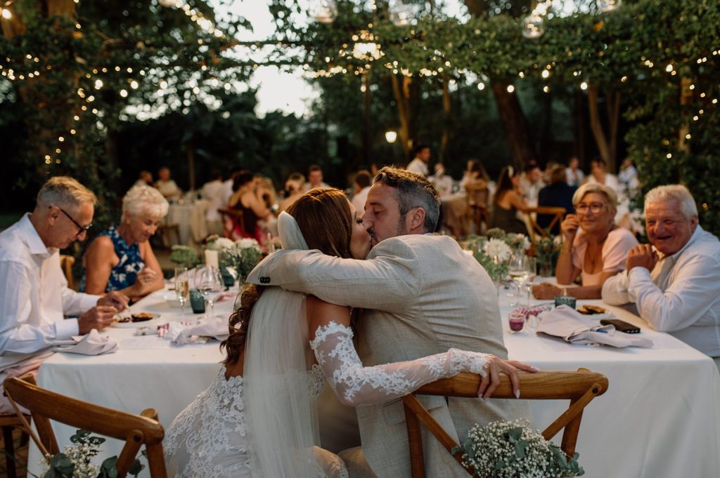 Couple sharing a romantic kiss at wedding reception.
